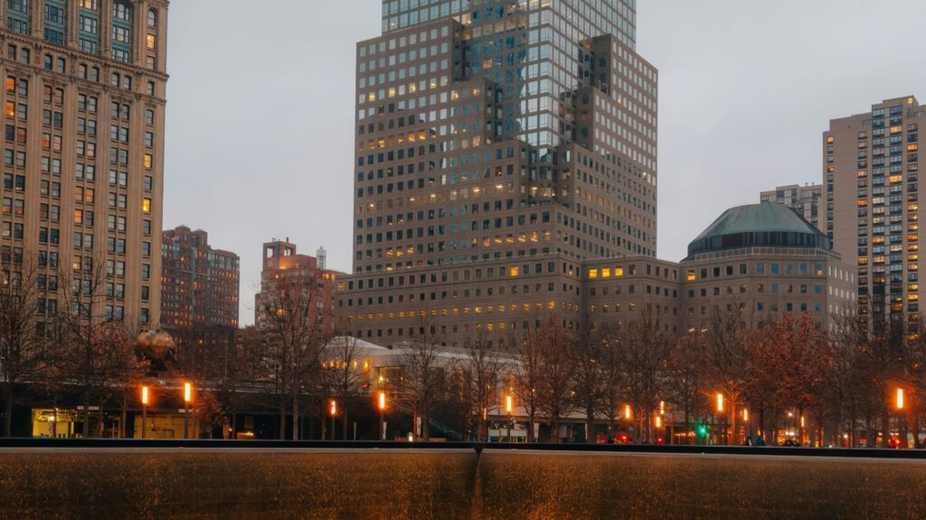 9/11 Memorial pool at the World Trade Center with Lower Manhattan skyline at dusk